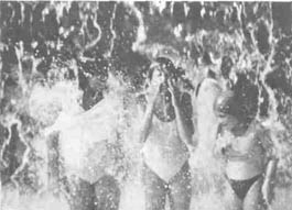 Swimmers play under a waterfall